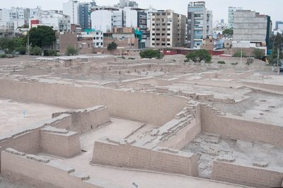 Huaca Pucllana — Excavated adobe foundations with modern Lima buildings behind
