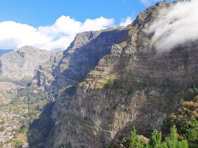 Miradouro Eira do Serrado — Layered cliffs and clouds frame the valley settlement below
