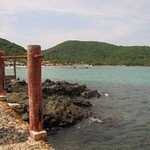 Playa Las Gatas — Rusty shoreline posts beside rocks and calm turquoise water